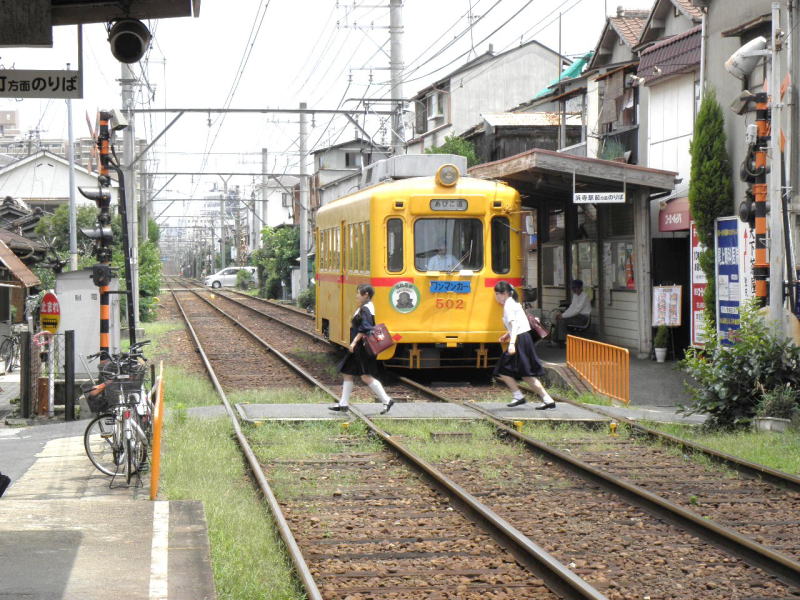 止まっている阪堺電車の前を小走りで渡る女学生